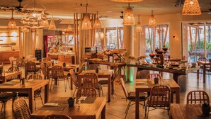 Un restaurante con muebles de madera, lámparas de mimbre colgantes y una zona de bar.