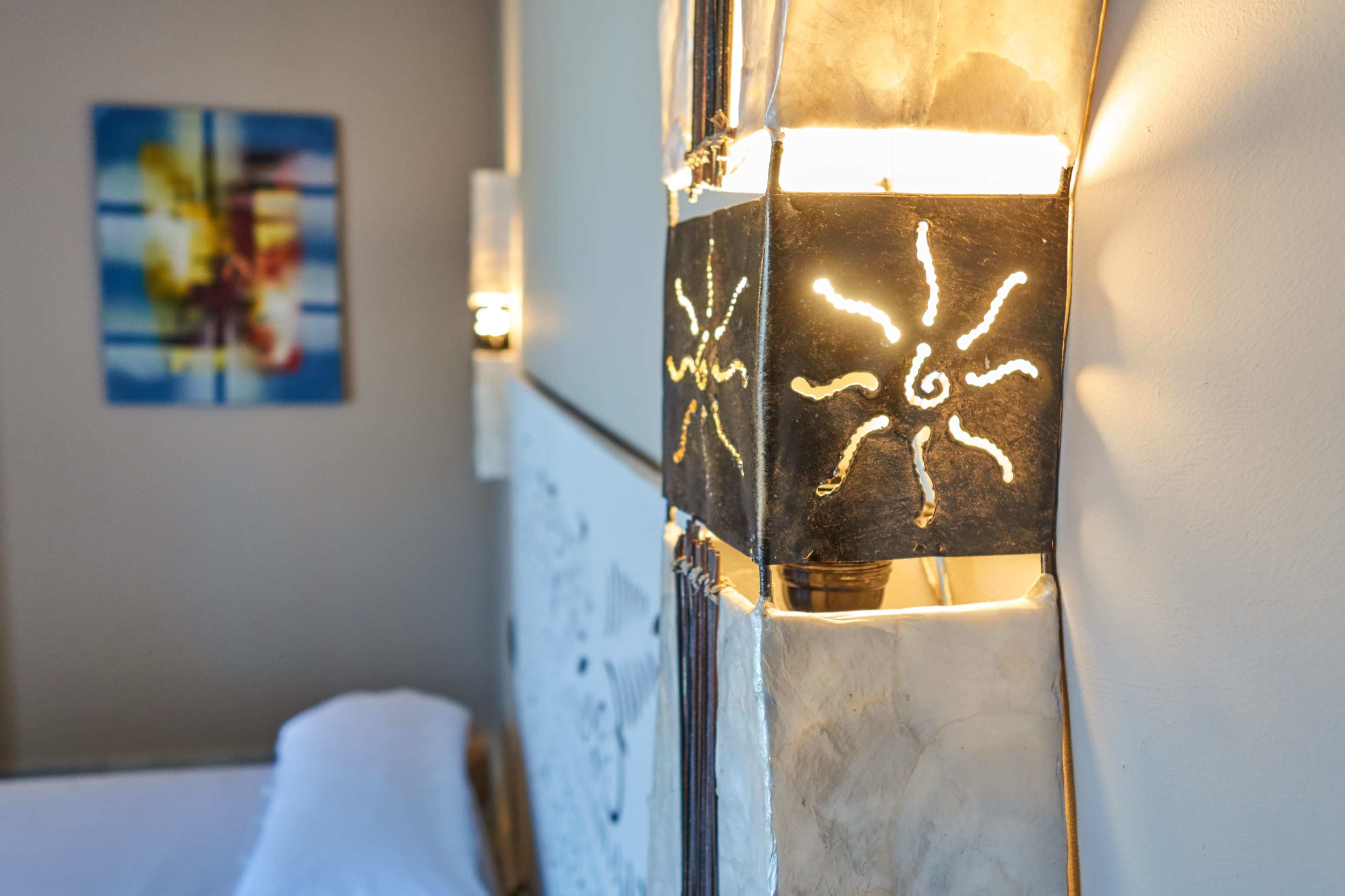 Una habitación de hotel con una cama, una lámpara de pared y un cuadro en la pared.