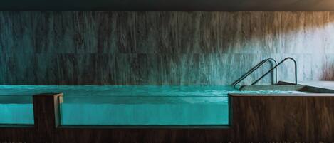 A swimming pool with a wooden deck and metal stairs.