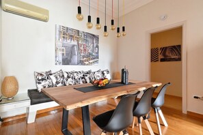 A dining area with a wooden table, black chairs, a black vase, and a fruit bowl. - Acropolis Exclusive Residences (Athens)