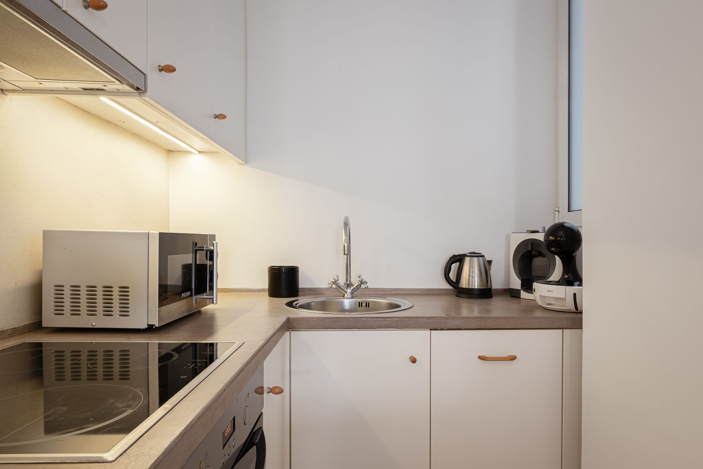 Eine moderne Küche mit Einbau-Mikrowelle, Edelstahl-Spüle und Kaffeemaschine.