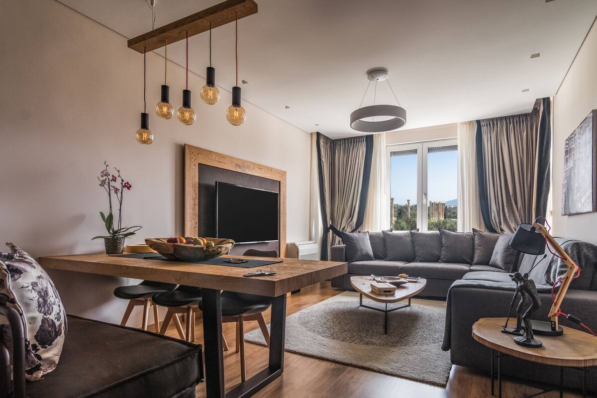 A modern living room with a wooden dining table, a sofa, and a TV.