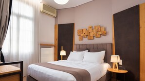 Una cama bien hecha con cabecera, una mesita de noche con lámpara y una obra de arte en la pared.