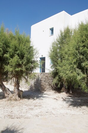 Un edificio blanco con entrada de pared de piedra, rodeado de árboles.