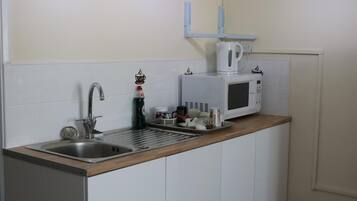Una cocina con un lavamanos de acero inoxidable, un microondas y una cafetera en la encimera.
