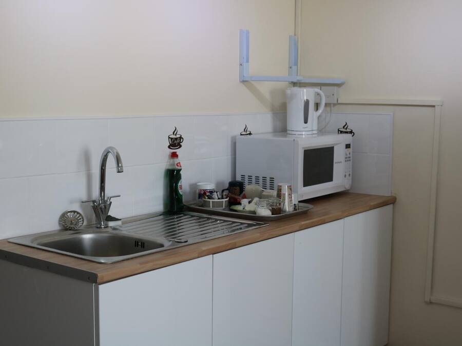 Una cocina con un lavamanos de acero inoxidable, un microondas y una cafetera en la encimera.