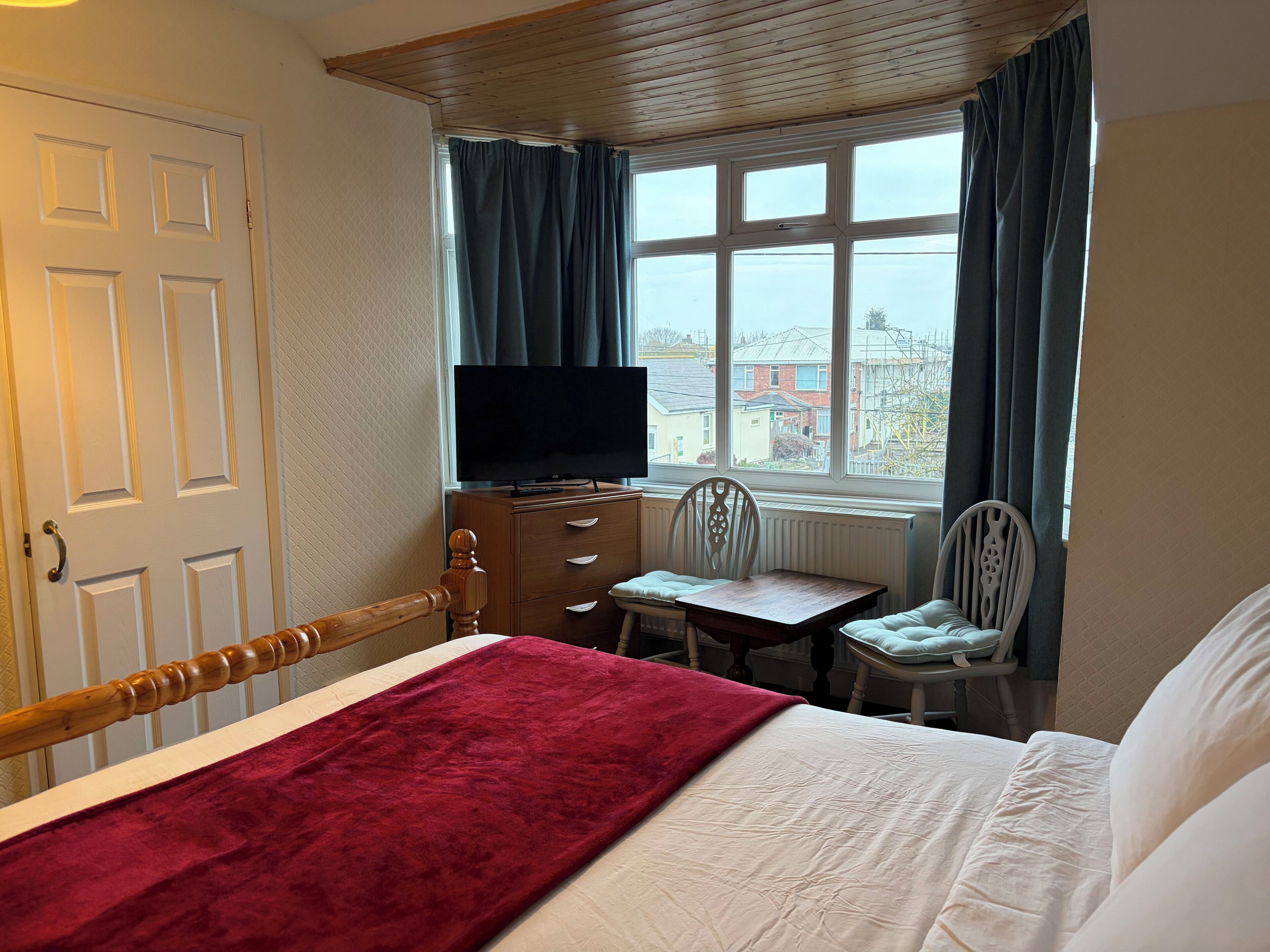 A hotel room with a bed, a desk, a chair, a television, and a window with curtains.