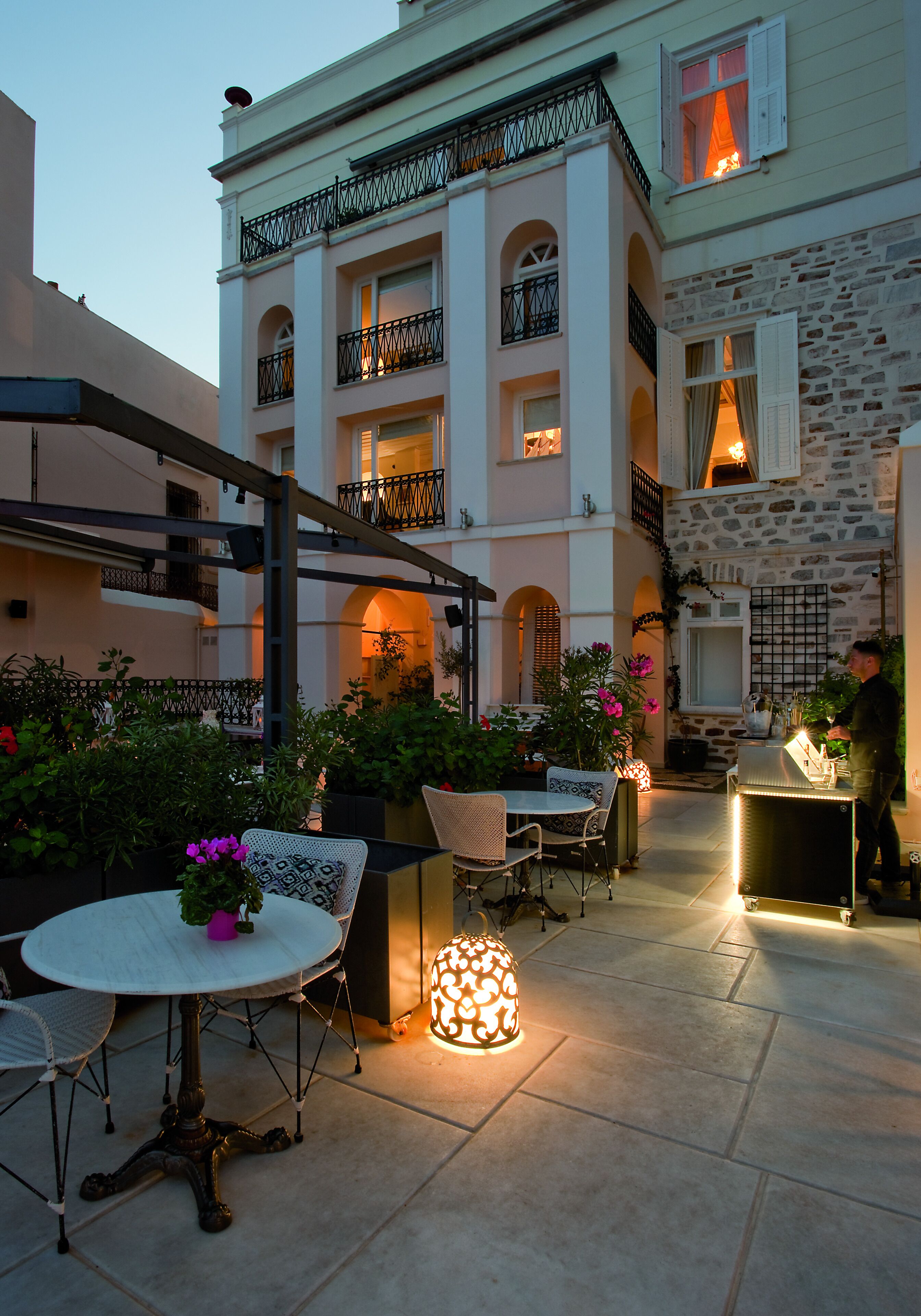 An outdoor patio area with tables and chairs, a decorative light, and a stone wall.