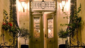 Una gran escala amb baranes de metall ornamentades i una gran planta en testos a la part superior.