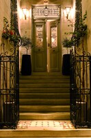A grand staircase with ornate metal railings and a large potted plant at the top.