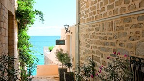 Un carreró empedrat de pedra amb plantes en testos i vista al mar.