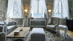 Una habitació acollidora amb parets de pedra, un sofà, una cadira, una taula petita i un llit.