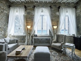 A cozy room with stone walls, a sofa, a chair, a small table, and a bed.