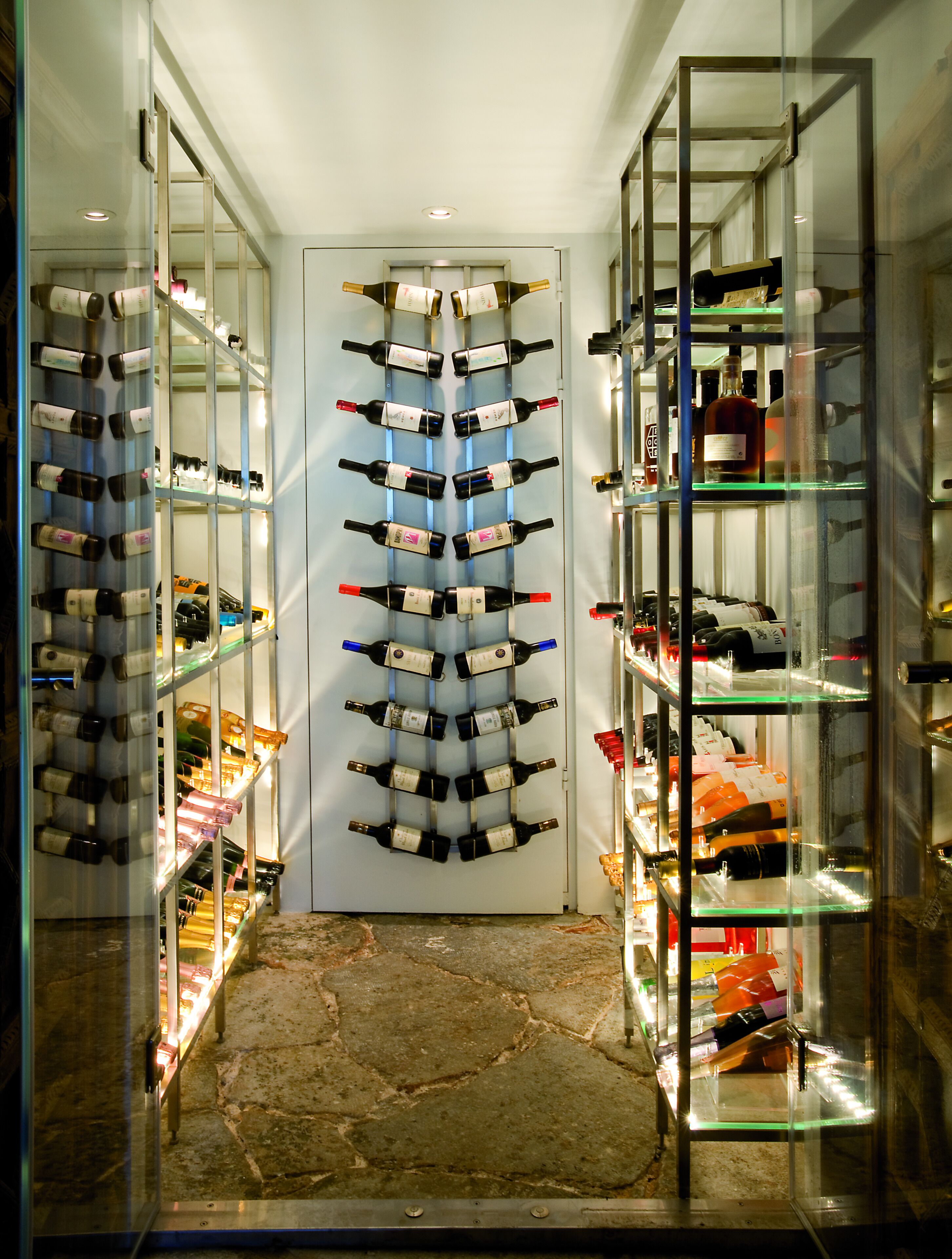 A wine cellar with shelves of wine bottles on both sides of a central aisle.