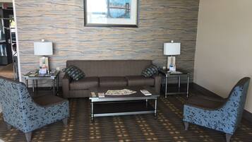 A modern living room with a brown sofa, two patterned armchairs, a coffee table, and two side tables with lamps. A framed picture hangs above the sofa.