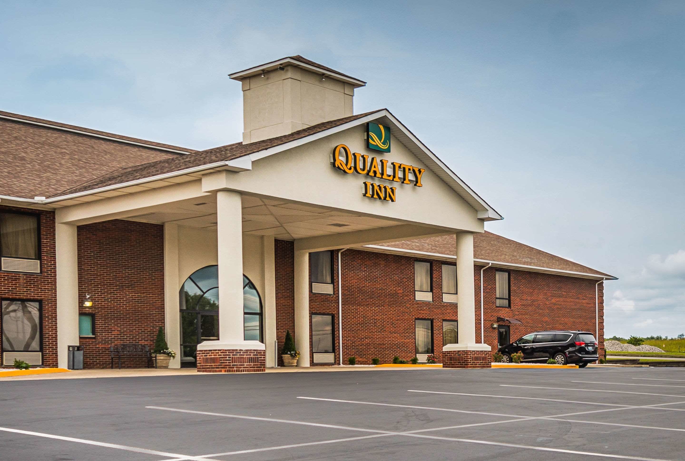 Un hôtel Quality Inn avec une façade en briques, une entrée couverte et un parking.
