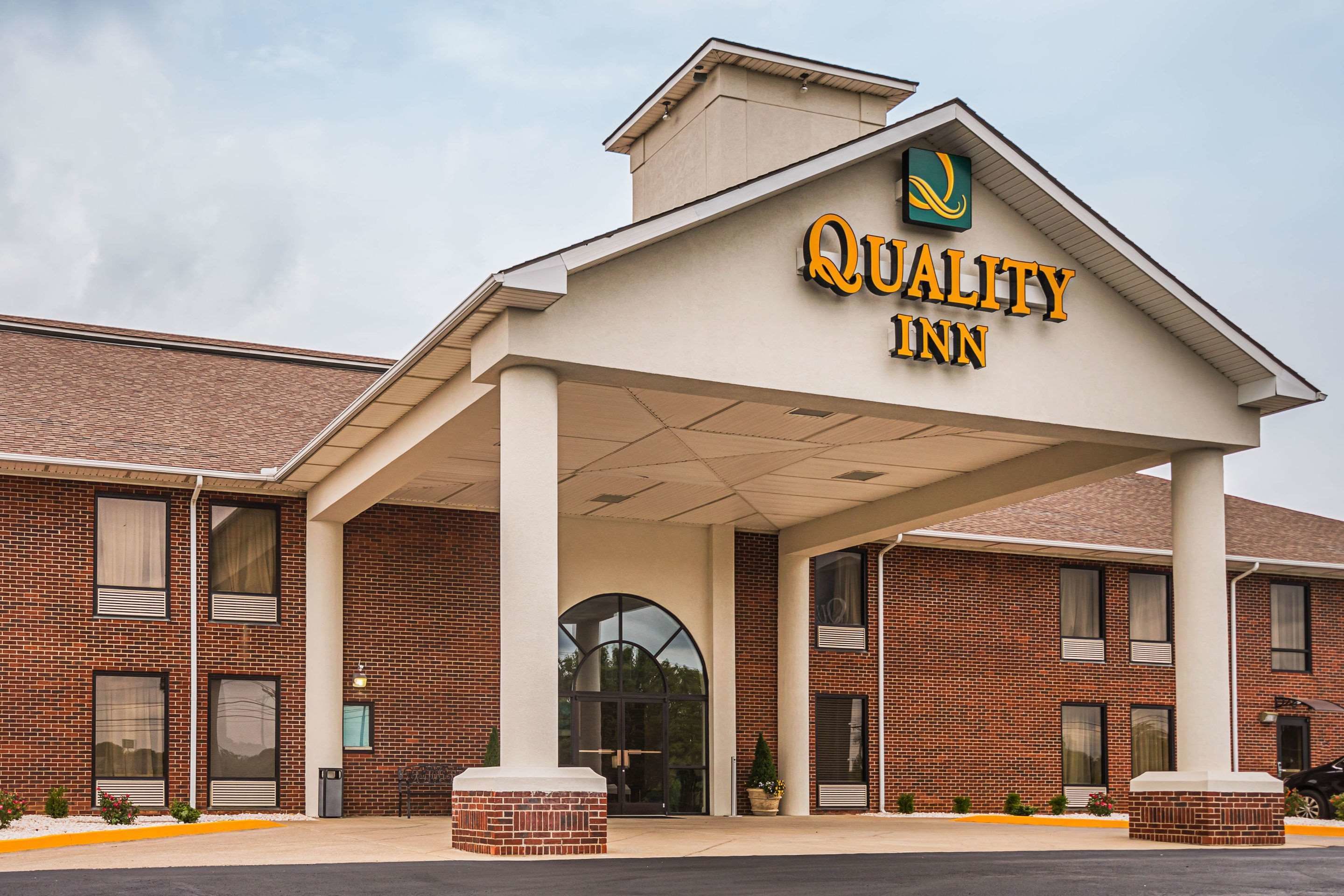 Un edificio de ladrillo con un vestíbulo cubierto que dice "Quality Inn".
