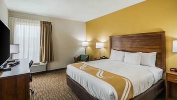 Une chambre d’hôtel avec un grand lit, un bureau avec un téléphone et une télévision.