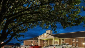 A Quality Inn with a brick exterior and a parking lot filled with cars.
