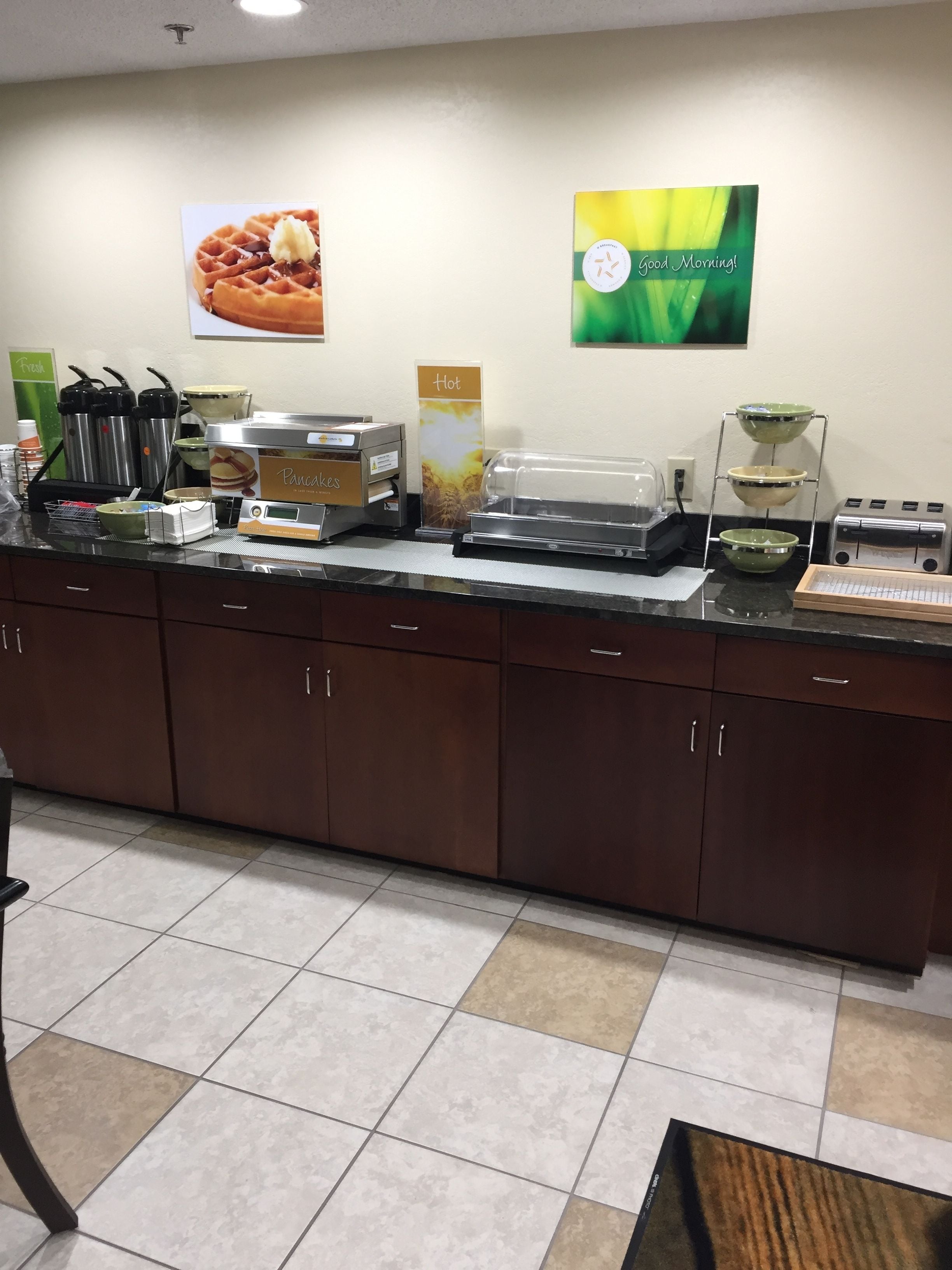 A breakfast station with waffle makers, a coffee machine, and a toaster.