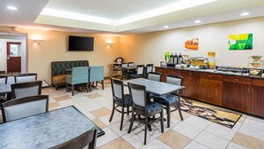 A restaurant with booths and tables, a counter with food items, and a television on the wall.