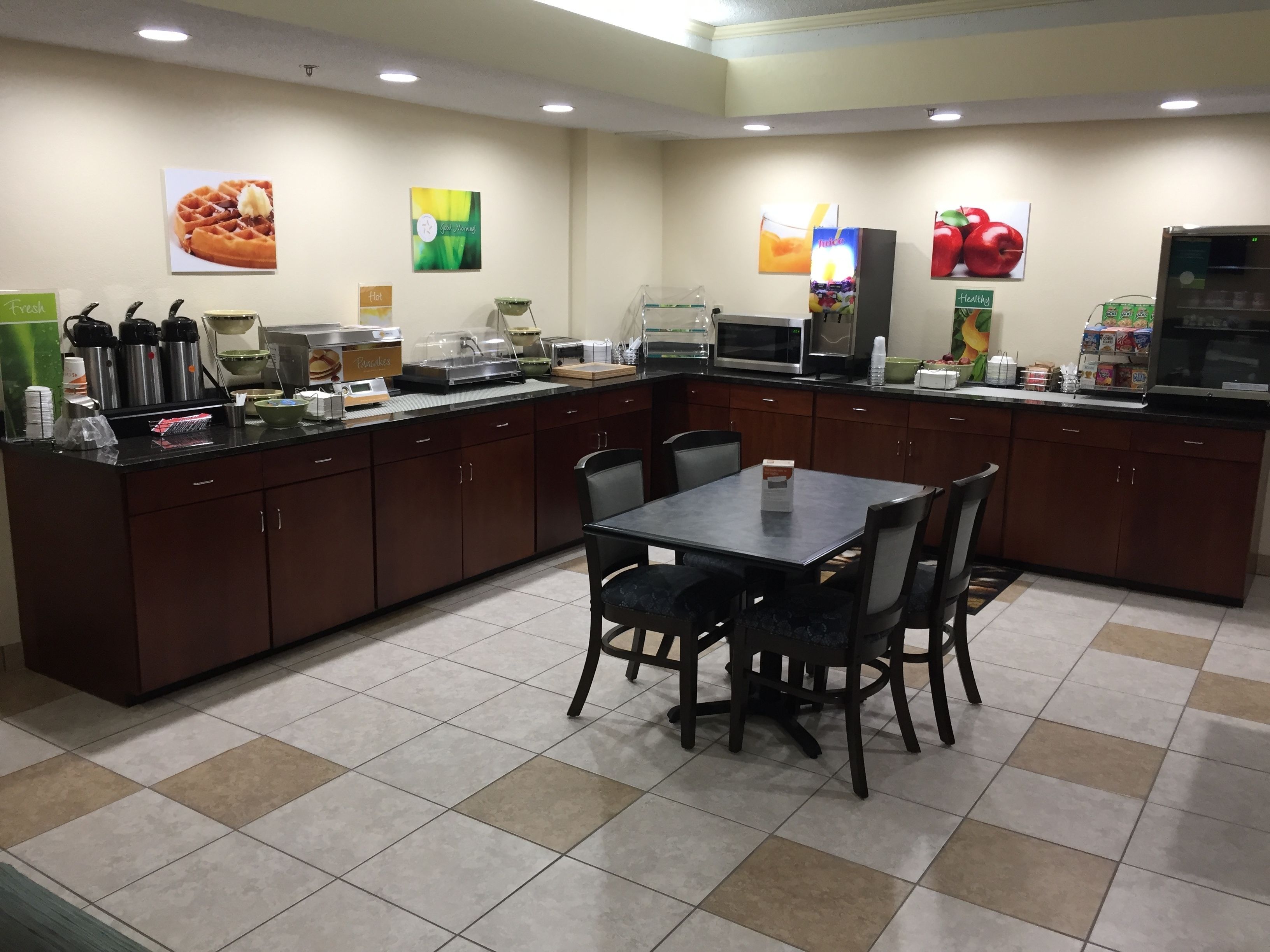 A kitchen area with a central island, a dining table with chairs, and various kitchen appliances and utensils.