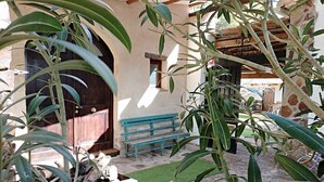 A courtyard with a wooden bench, a door, and a wall with a window. - Apartamentos Rurales Las Caleras (Almagro)