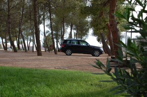 Un SUV negre aparcat en una zona d'aparcament envoltada d'arbres.