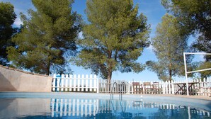 A swimming pool with a white picket fence and trees in the background. - Apartamentos Rurales Las Caleras (Almagro)