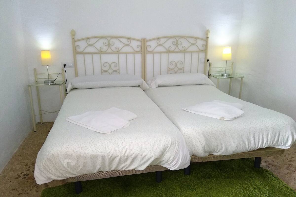 A double bed with a metal headboard, two bedside tables with lamps, and a green carpet.
