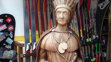 A wooden statue of a historical figure with a headdress, surrounded by skis.