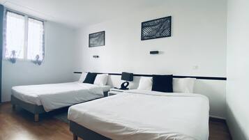 A hotel room with two single beds, a large window with curtains, and a wall-mounted artwork.