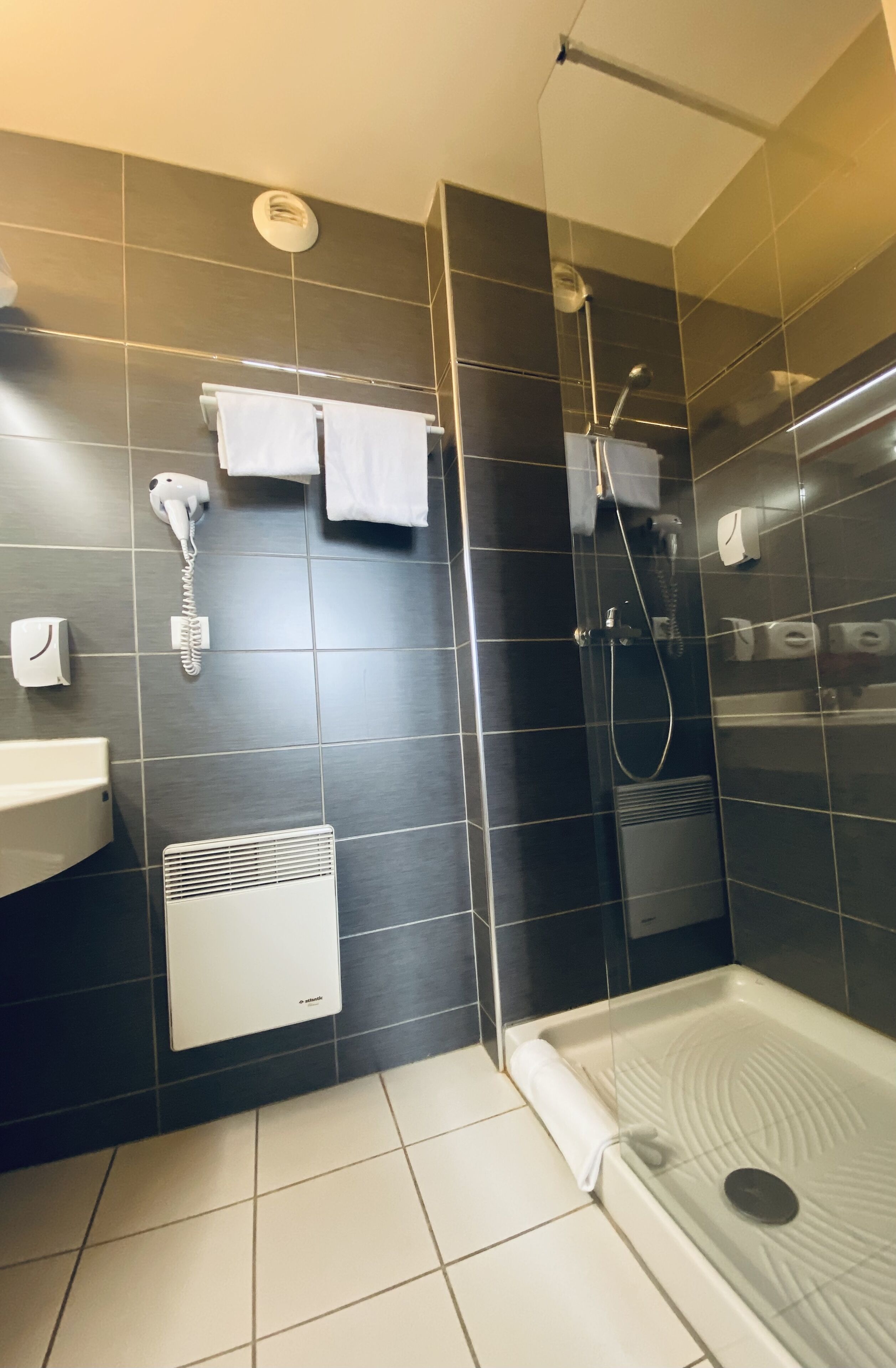 Ein modernes Badezimmer mit einer gläsernen Duschkabine, einem weißen Waschbecken auf Säule und einer integrierten Heizung.