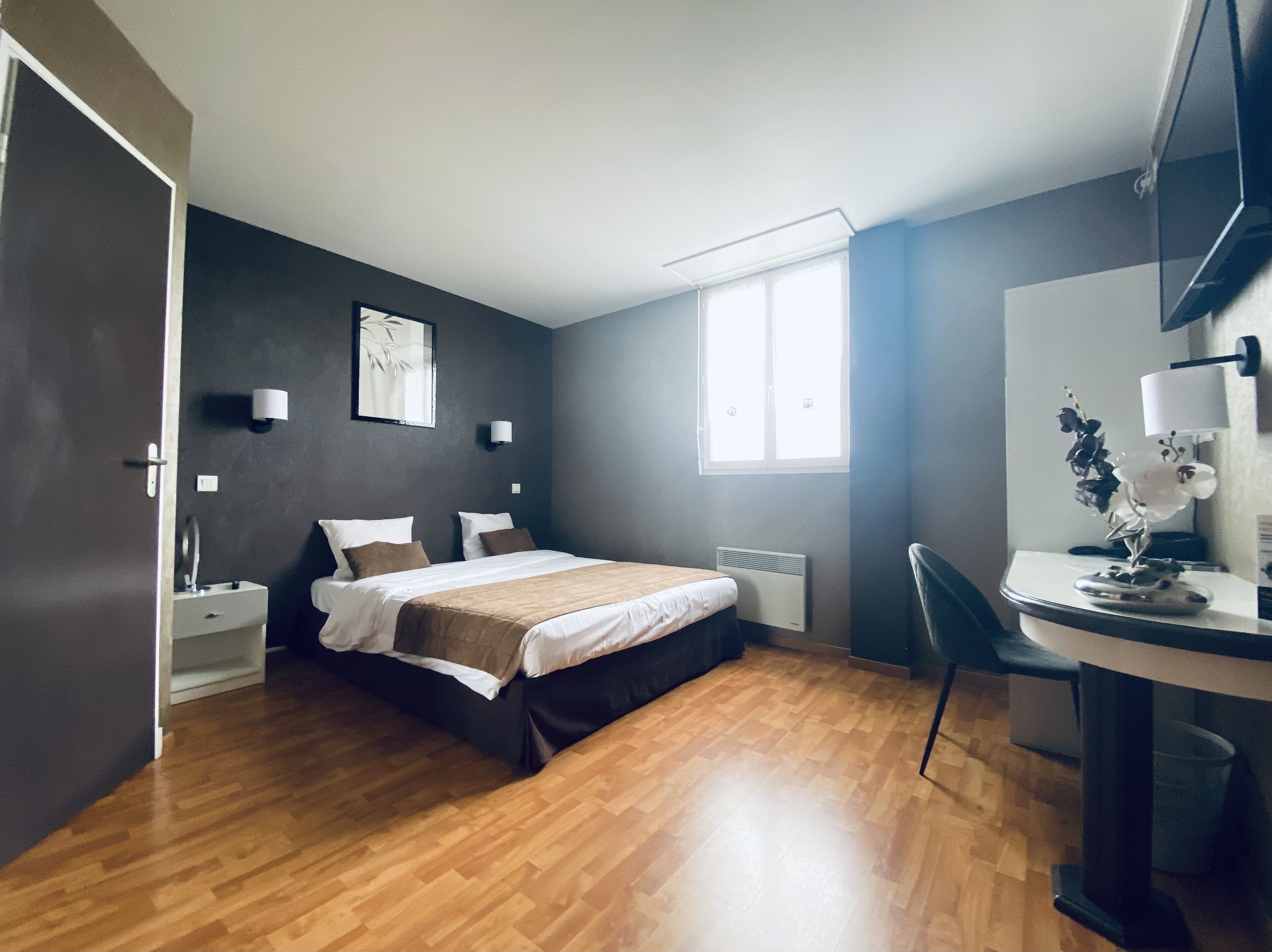 A modern bedroom with a bed, bedside tables, a desk, and a chair.