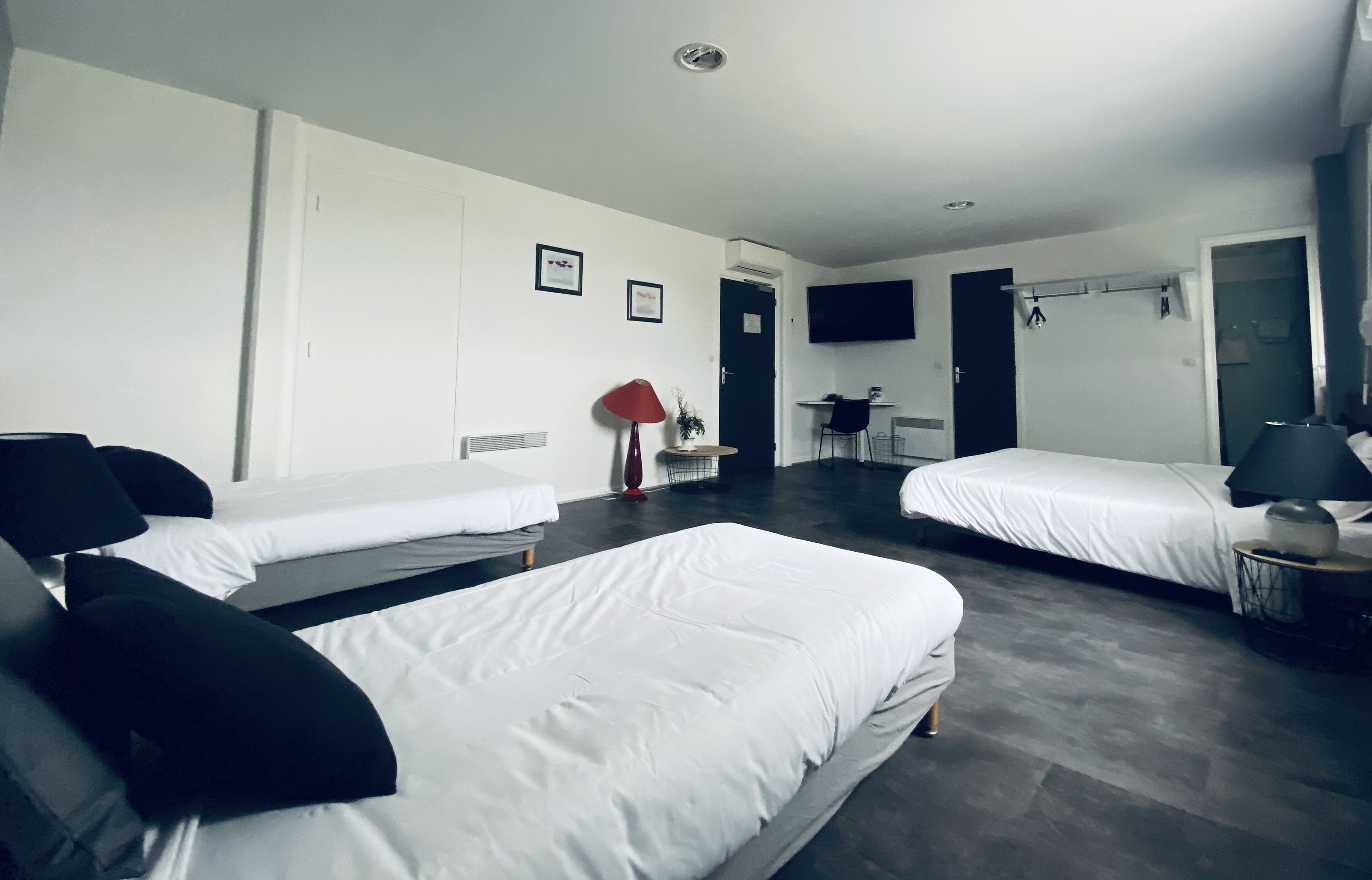 Hotellihuone, jossa on kaksi erillistä sänkyä, työpöytä, tuoli ja seinälle asennettu televisio.