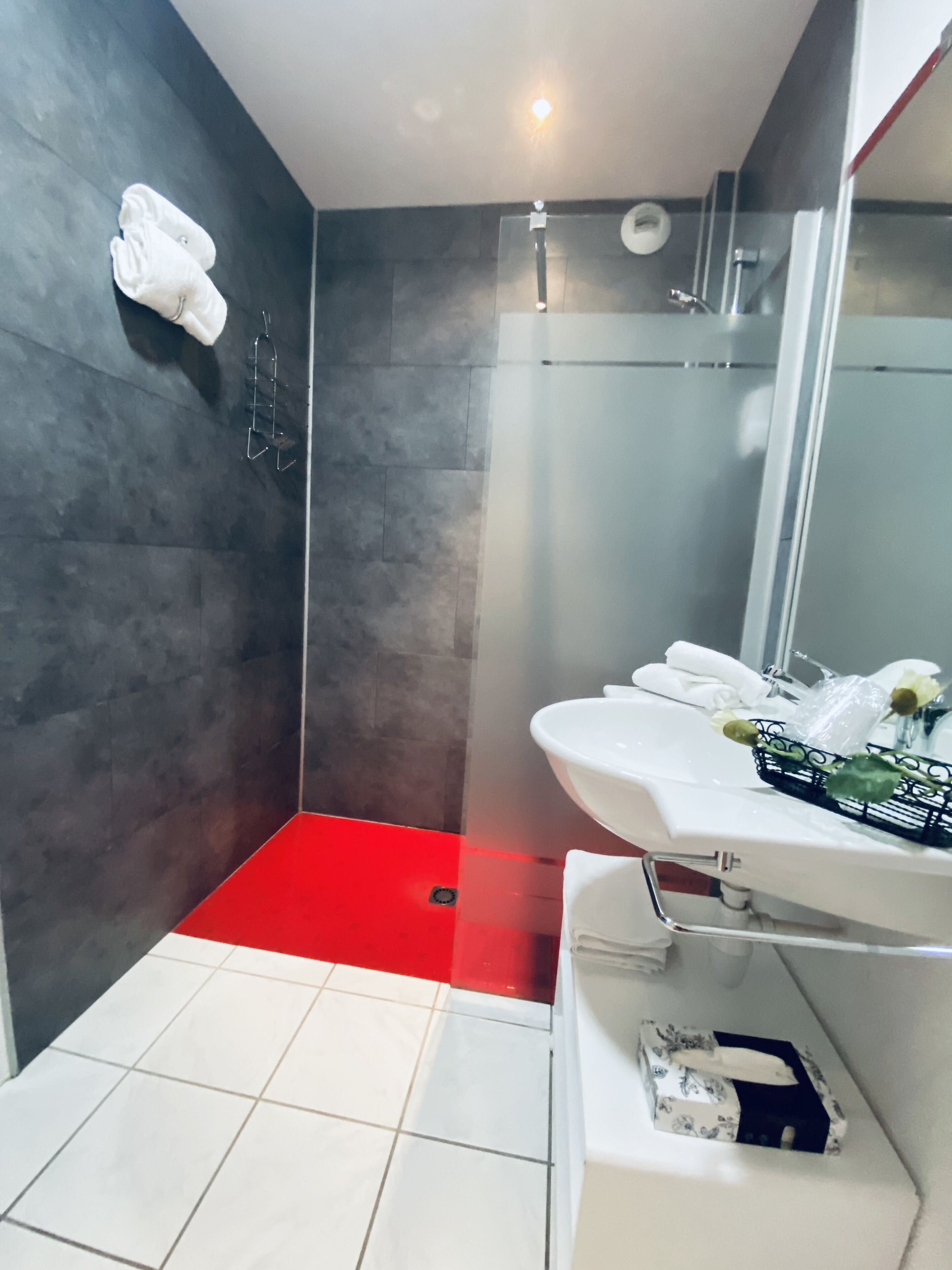 Uma casa de banho moderna com chuveiro, lavatório branco e espelho.
