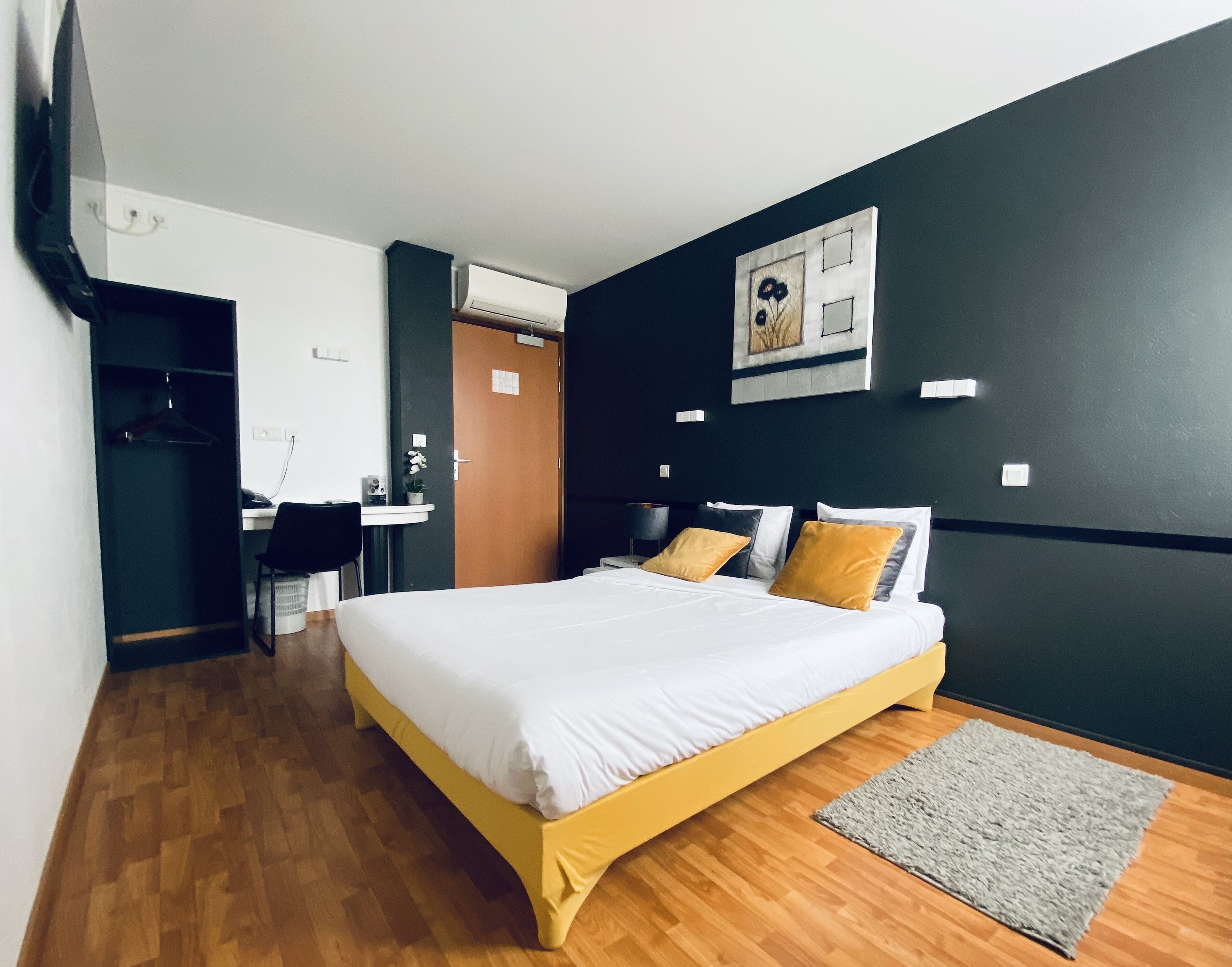 A hotel room with a bed, a desk, and a chair.
