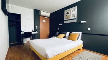 A hotel room with a bed, a desk, and a chair.
