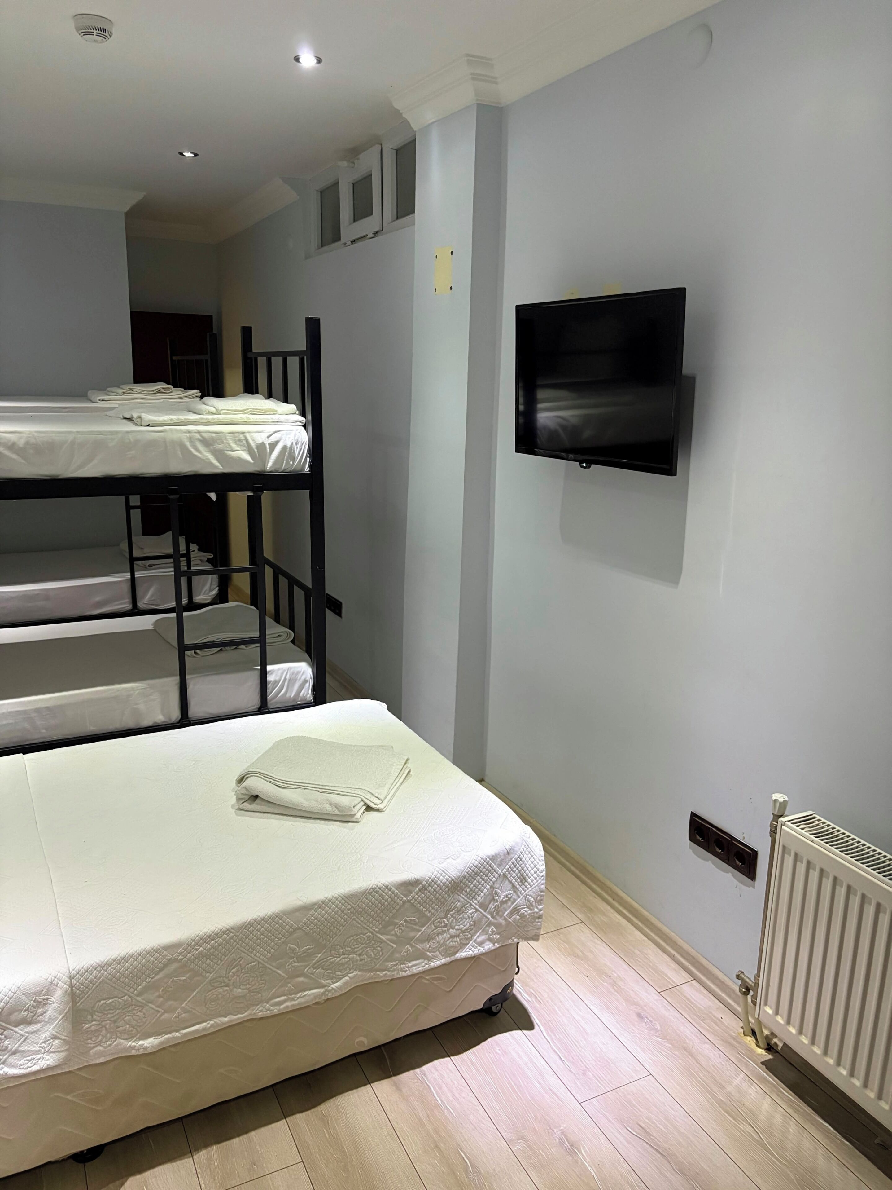 Une chambre avec des lits superposés, un téléviseur à écran plat et un radiateur.