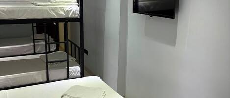 Une chambre avec des lits superposés, un téléviseur à écran plat et un radiateur.