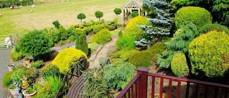A garden with a gazebo, neatly trimmed hedges, and a wooden deck.