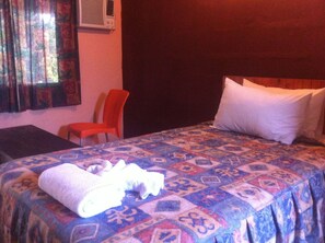 A hotel room with a bed, a chair, a table, and a window with curtains. - Alfa Accommodation (Maun)