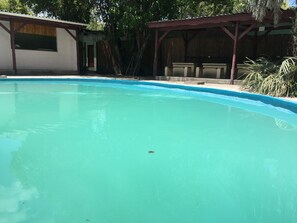 Piscina cristalina con cubierta de madera y zona de estar techada.