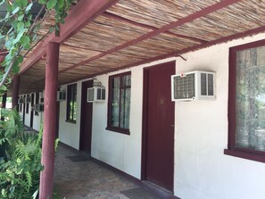 Un pasillo cubierto con varias puertas, unidades de aire acondicionado y piso de baldosas.