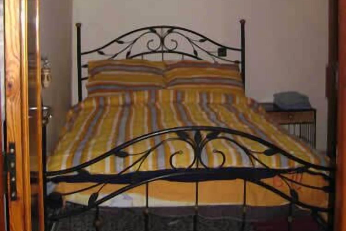 A room with a bed, a wall-mounted light fixture, and a small table.