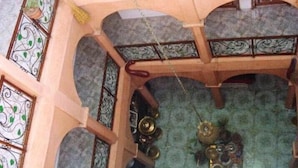 Una habitación con techo alto, barandillas de metal ornamentadas y alfombra estampada.