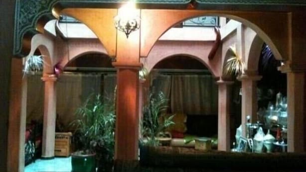 Una habitación con un arco tradicional, una araña y plantas en macetas.