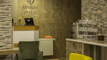 A hotel reception area with a reception desk, a computer, a telephone, and a wall-mounted sign reading "SIMŞIR OTEL".