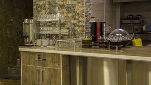 Et moderne køkken med bagvæg af mursten, rustfrie hvidevarer og et buffetbord med klare glas og et klokkeformet låg.