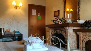 A hotel room with a bed, a fireplace, a mirror, and wall-mounted lamps. - Selene Policlinico di Catania (Gravina di Catania)